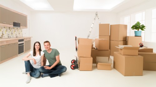 Moving team assisting with boxes and furniture in Sutton flat